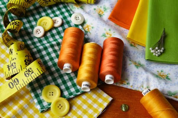 Thread, buttons, measuring tape on desk --- Image by © Debby Lewis-Harrison/cultura/Corbis
